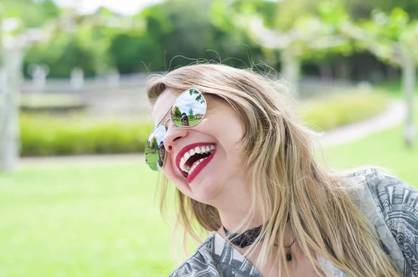 Young happy blonde woman laughing on the lawn.