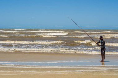 Genç adam plajda, balıkçılık spor balıkçılık.
