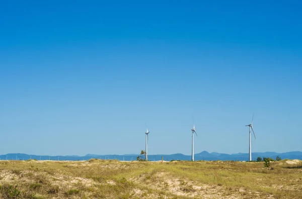 Great concept of renewable, sustainable energy. Wind field with wind turbines, producing aeolian energy under blue sky.