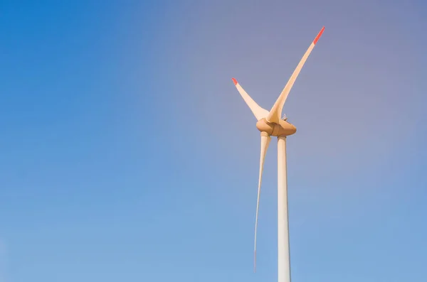 Great concept of renewable, sustainable energy. Wind field with wind turbines, producing aeolian energy under blue sky.