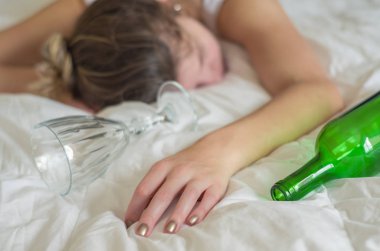 Büyük kavram, alkol. Genç kadın, sarışın, çok fazla alkol içtikten sonra yatakta bayıldı. El, bir şişe şarap şarap.