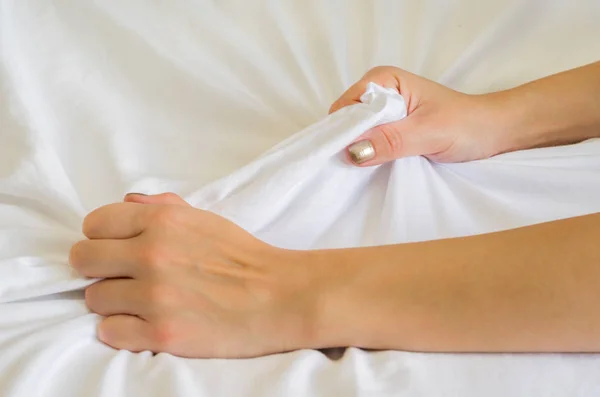 白いベッドの上の女性の手のサインオーガズム エクスタシーで白いシートを引っ張る女性の手 感覚と感情の概念 — ストック写真