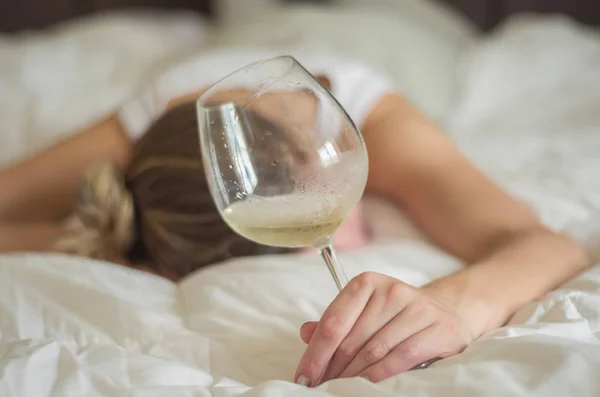 酒精滥用的伟大概念 年轻女人 喝了太多酒后晕倒在床上 手里拿着酒杯 一瓶酒 — 图库照片