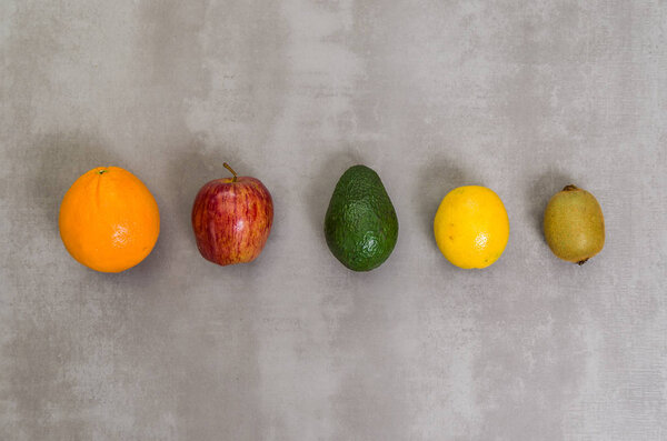 Great concept of healthy eating, various fruits on gray background, polished concrete. Orange, apple, kiwi, lemon.