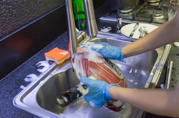 Cleaning the dishes, pot in the sink.