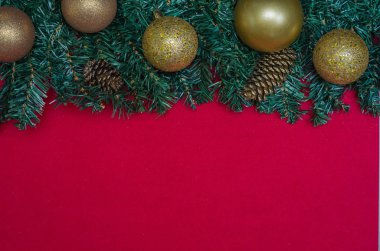 Doku Noel tema yeşil yaprakları, dekoratif objeler ve kırmızı arka plan ile. Kopya alanı ile.