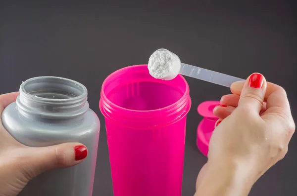 Sport, fitness, healthy lifestyle and people concept - close up of women with jar and bottle preparing protein shake