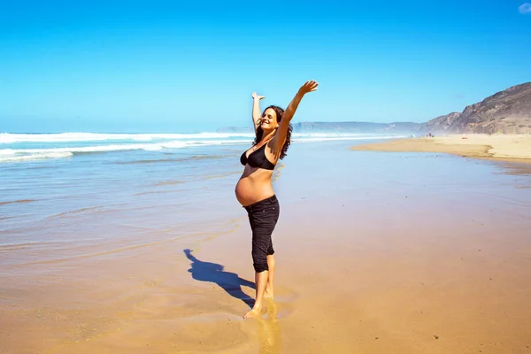 Glad gravid kvinna på stranden vid Atlanten — Stockfoto