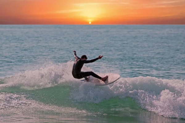 El joven coge una ola en su tabla de surf en la isla de Aruba en el — Foto de Stock