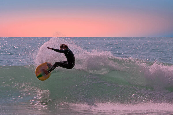 Young man catches a wave on his surfboard on Aruba island in the