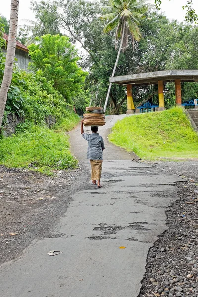 Balinese man in traditionele kleding die huishoudelijke goederen vervoeren op — Stockfoto