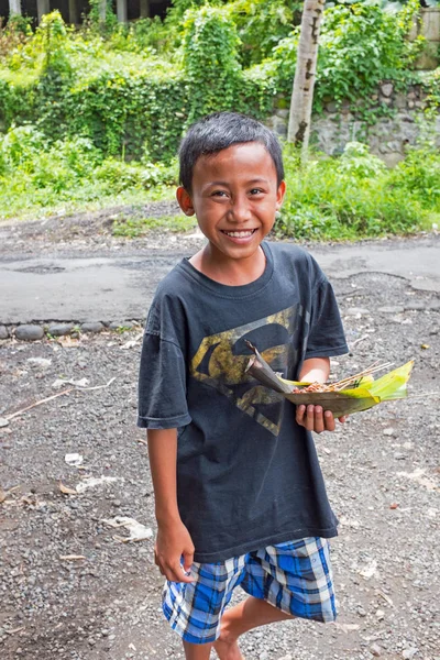 BALI, INDONESIA - DECEMBER 25, 2016: Young boy just got his food — Stock Photo, Image