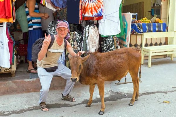 Turista con una mucca di fronte a un negozio di abbigliamento a Laxman Jhula I — Foto Stock