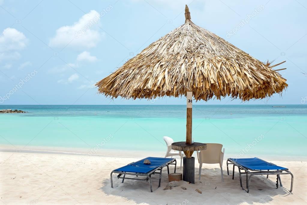 Beach umbrella and beach chairs on Palm Beach at Aruba island in