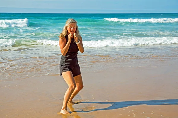 Sportive mature woman doing kickbox training at the beach at the — Stock Photo, Image