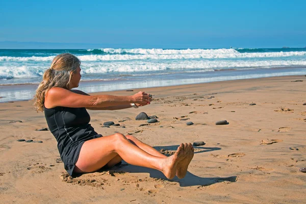 Sportos érett nő csinál tornák a strandon a Tünde — Stock Fotó