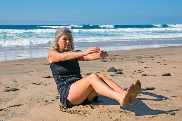 Sportive mature woman doing excercises at the beach at the atlan — Stock Photo, Image