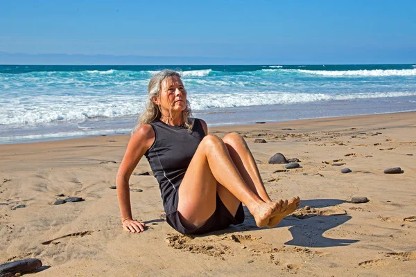 Sportliche reife Frau macht Übungen am Strand am Atlan — Stockfoto