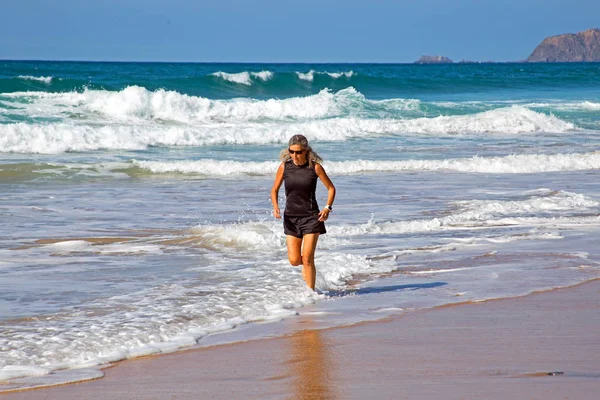 Sportliche reife Frau macht Übungen am Strand am Atlan — Stockfoto