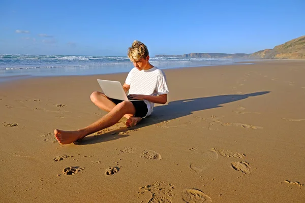 在海滩工作的年轻人在他的笔记本电脑上 — 图库照片