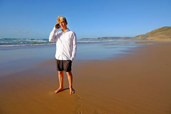 Młody facet na plaży wykonujący telefon — Zdjęcie stockowe