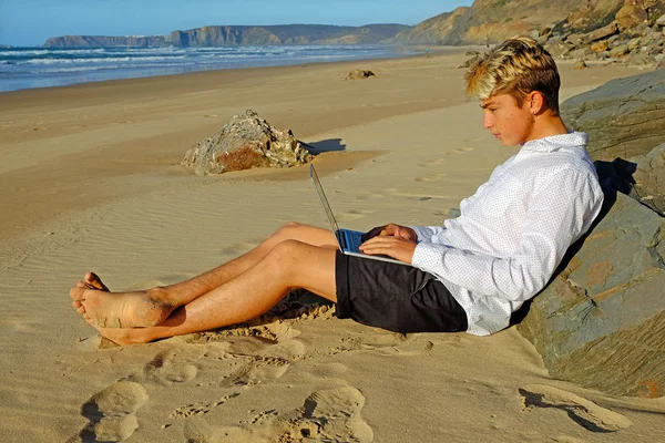 Νεαρός στην παραλία που φτιάχνει το λάπτοπ του. — Φωτογραφία Αρχείου