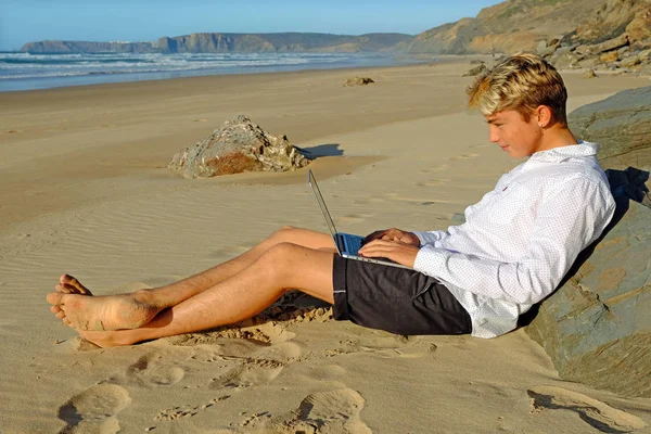 Joven en la playa trabajando en su portátil — Foto de Stock