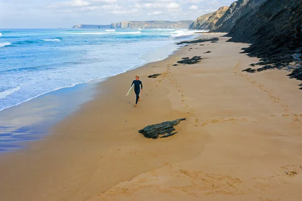 Antenne eines jungen Surfers, der am Strand am Atlantik entlang läuft — Stockfoto