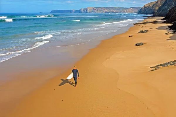 Aerial de um jovem surfista caminhando ao longo da praia no atlante — Fotografia de Stock