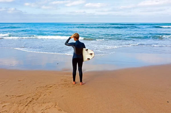 Jovem olhando para as ondas antes de surfar — Fotografia de Stock