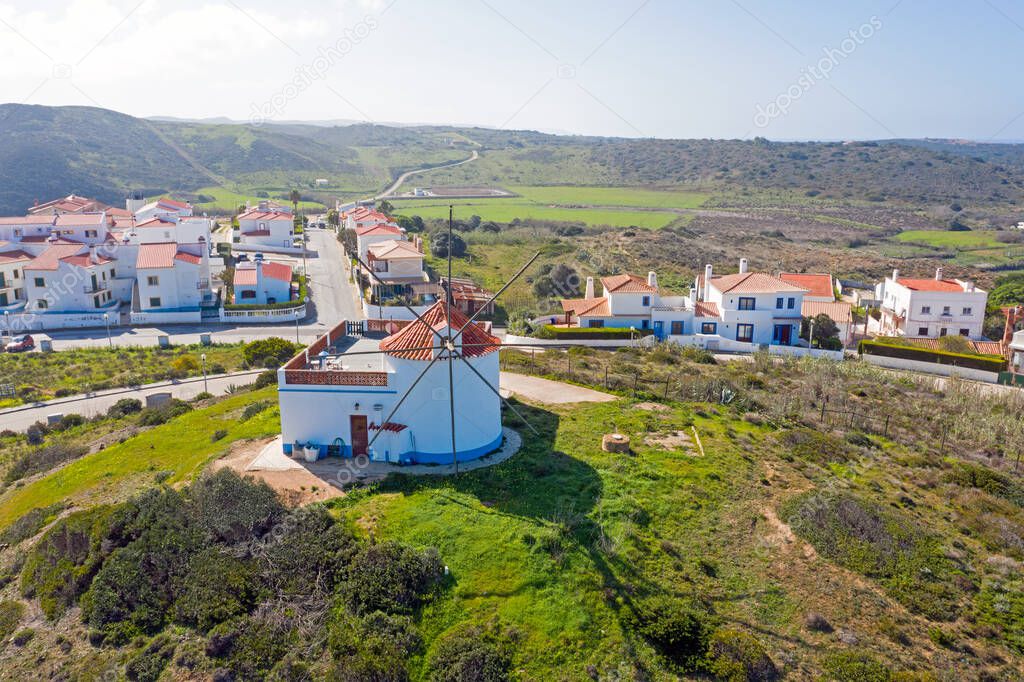 Aerial from the village Carapateira on the westcoast in Portugal with an old traditional windmill