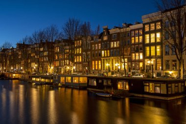 Amsterdam 'da geleneksel evler ve tekneler gün batımında Hollanda' da