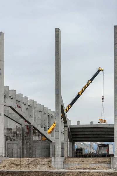 Workers build a new stadion. Concrete and steel building. Construction with a crane