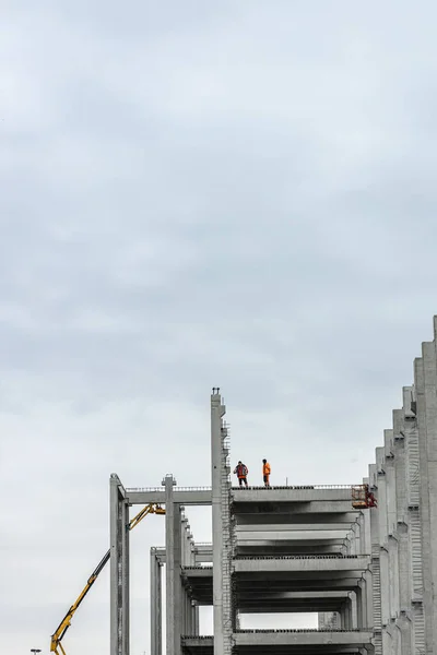 Workers build a new stadion. Concrete and steel building. Construction with a crane