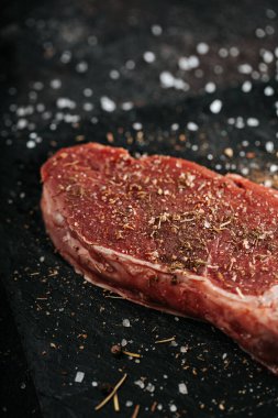 Biber ve tuz serpiştirilmiş sığır filetosu. Evdeki siyah mermer tabakta taze et. Baharatlı biftek..