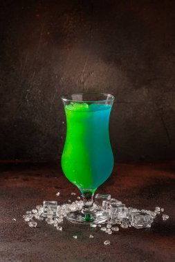 Esmer zemin üzerinde meyveler olan lezzetli buzlu kokteyl. Masada buzlu sağlıklı renkli meyveler sallanıyor..