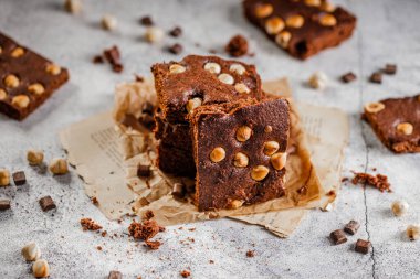 Koyu çikolata ve kakaolu kek açık gri beton masa, çikolata ve fındık parçaları.