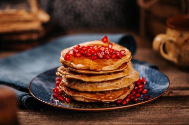 Lezzetli pekmezli Amerikan krepleri mavi bir tabakta eski ahşap masanın üzerinde.