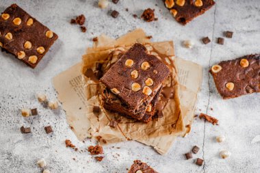 Koyu çikolata ve kakaolu kek açık gri beton masa, çikolata ve fındık parçaları.