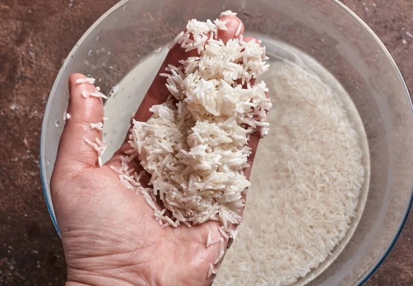 white basmati rice in water in a glass bowl on a brown background