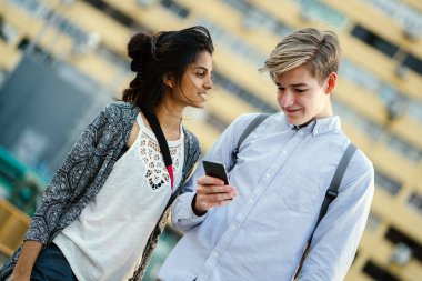 Bir genç çekici turist çift ayakta ve gün boyu birlikte açık havada portresi. Hint ve erkek beyaz kadındır. Belki de yol tarifi için bir telefon bakıyorlar.