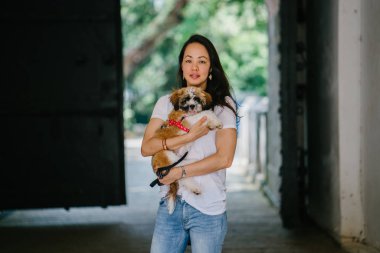 Genç bir kız ve köpeği portresi. Pan Asya kadın çekici ve raslantı giyimli ve onun Shih Tzuh onun kollarında taşıyor ve yumuşak gülümsüyor.