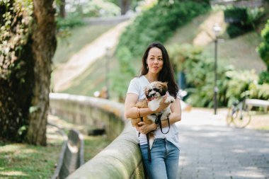 Parkta onun shih tzuh köpek olan bir genç, çekici pan Asya kadın portresi. Onlar ortasında bir yürüyüş ve neşeli ve rahat görünüyorlar.
