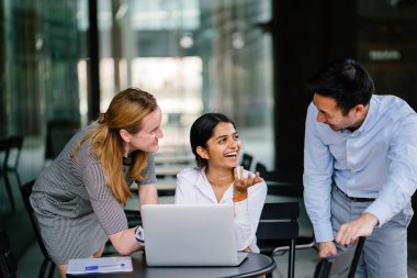 farklı bir takım 3 kişi bir dizüstü bilgisayar etrafında bir tartışma gün açık bir alanda yaşıyorsanız. Gülümse ve konuşmak gibi enerjik ve neşeli vardır.