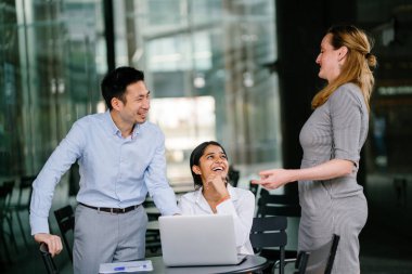 farklı bir takım 3 kişi bir dizüstü bilgisayar etrafında bir tartışma gün açık bir alanda yaşıyorsanız. Gülümse ve konuşmak gibi enerjik ve neşeli vardır.