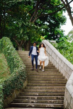 Interracial aşıklar çifti parkta taş merdivenlerden gün boyunca çalıştırın. Bir Hintli Çinli bir kadını evleniyor ve onlar zevk ve neşe içinde merdivenlerden aşağı çalışan.