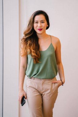 Bir çekici, genç Singapurlu kadını rahat çatı dairesinde portresi. O bir pencere yanında duran ve contentedly gülümseyen.