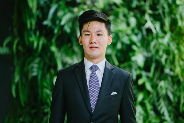 Portrait of Asian man in a professional dark suit and white shirt . He has a stylish pocket square