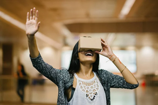 A young and photogenic Indian woman tries virtual reality goggles for the first time. She is smiling and laughing in delight and surprise at the experience