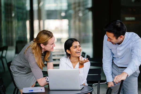 farklı bir takım 3 kişi bir dizüstü bilgisayar etrafında bir tartışma gün açık bir alanda yaşıyorsanız. Gülümse ve konuşmak gibi enerjik ve neşeli vardır.